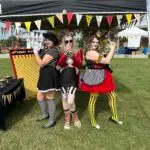 Ladies of the Peddler's Post posing in front of their booth at Cooterween hosted by the Twistid Arts Initiative in downtown Inverness, FL. 2023