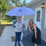 Amy posing with Shavonne our October 2023 Hernando County Umbrella Winner pictured outside of the winner's home in Brooksville FL
